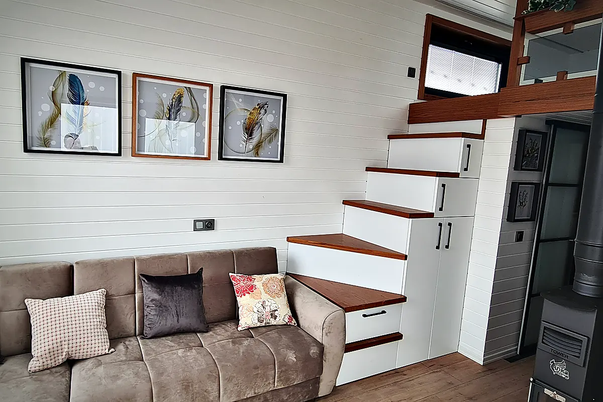 Wohnbereich mit Sofa und Treppe mit integrierten Schubladen zum Schlafloft