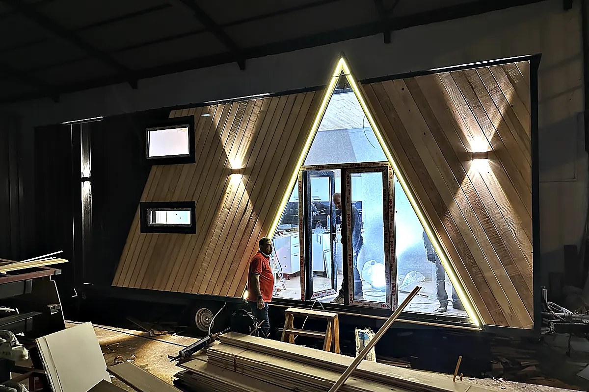 A-Frame-Einheit im Rohbau in der Werkhalle, Holzschalung montiert, Zuschnitte auf dem Boden