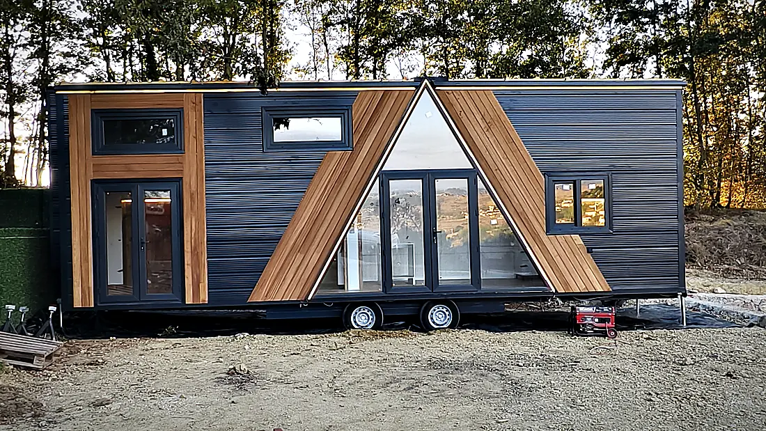 Stahlrahmen im Vordergrund, fertiggestelltes Tiny House dahinter auf dem Werksgelände