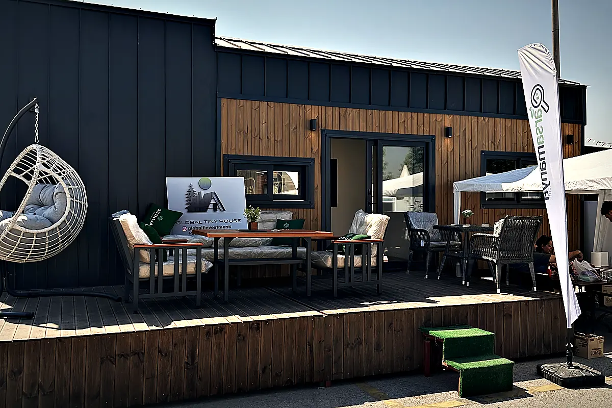 Einheit mit Holz- und Metallfassade, davor eine Terrasse mit Tisch, Stühlen und Hängesessel
